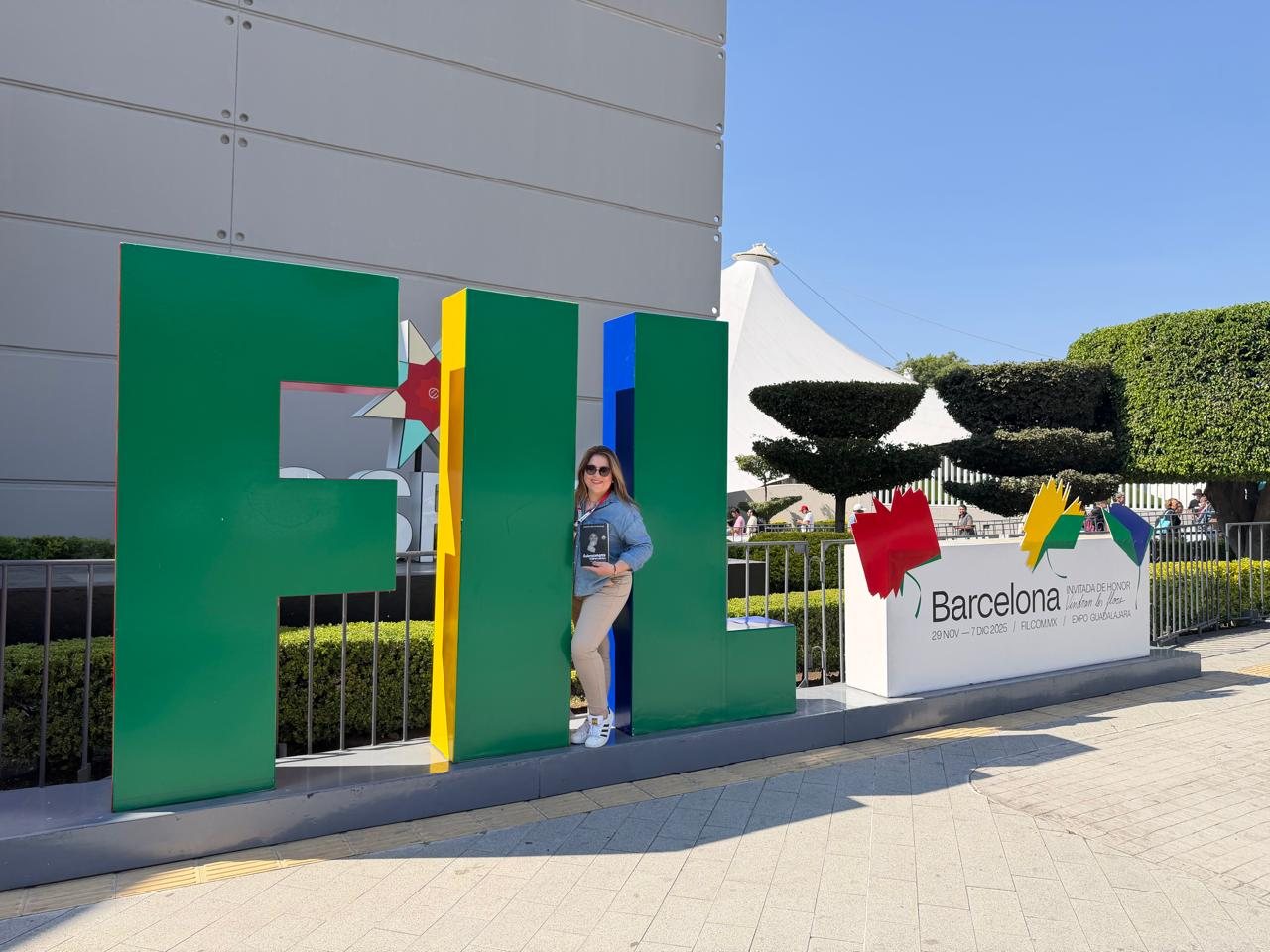 Jennifer Sierra con el libro frente a las letras FIL en Expo Guadalajara